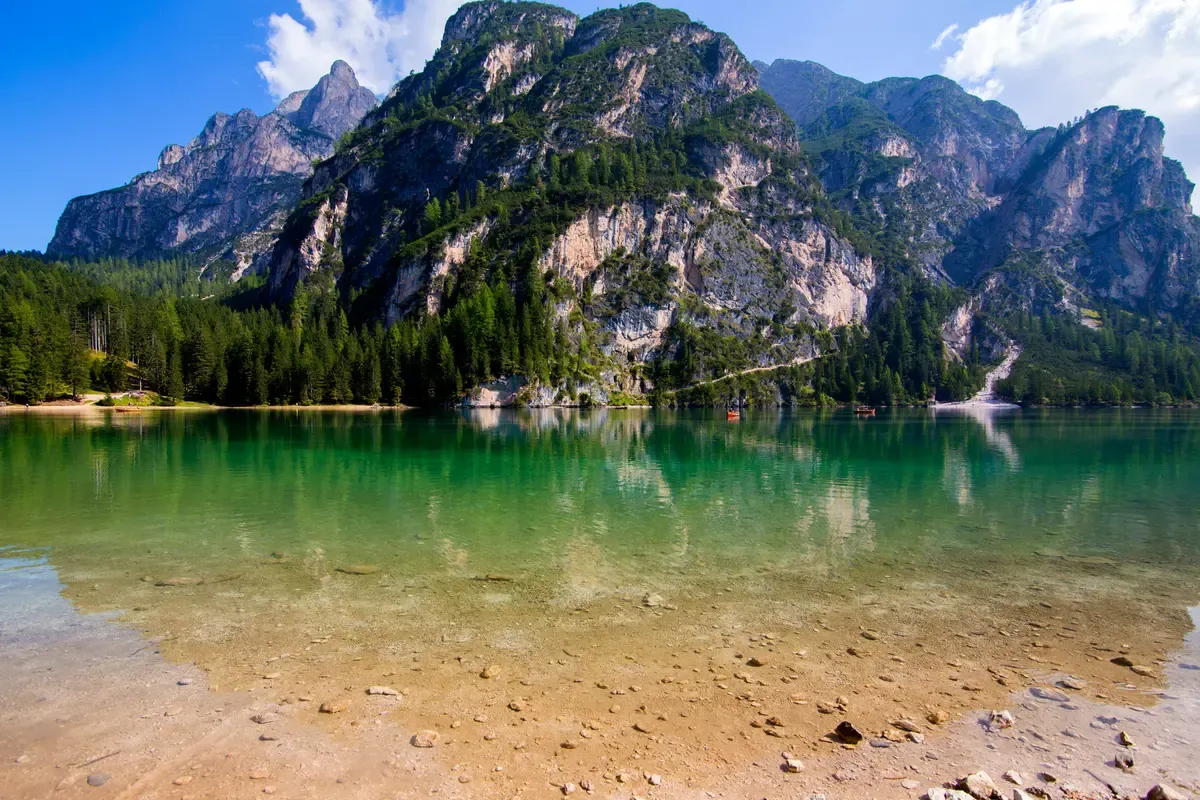 Green shallow water of Lake Braies below steep limestone walls