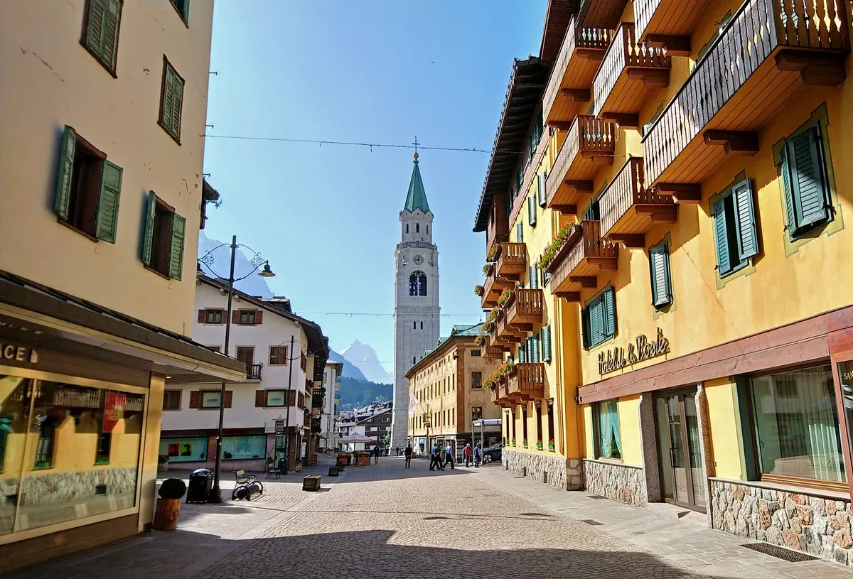 Corso Italia in Cortina d'Ampezzo, a pedestrian street with the bell tower and mountains at the end