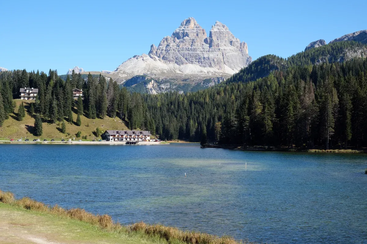 Tre Cime di Lavaredo rising beyond Lake Misurina and pine forest, why the Dolomites are worth visiting